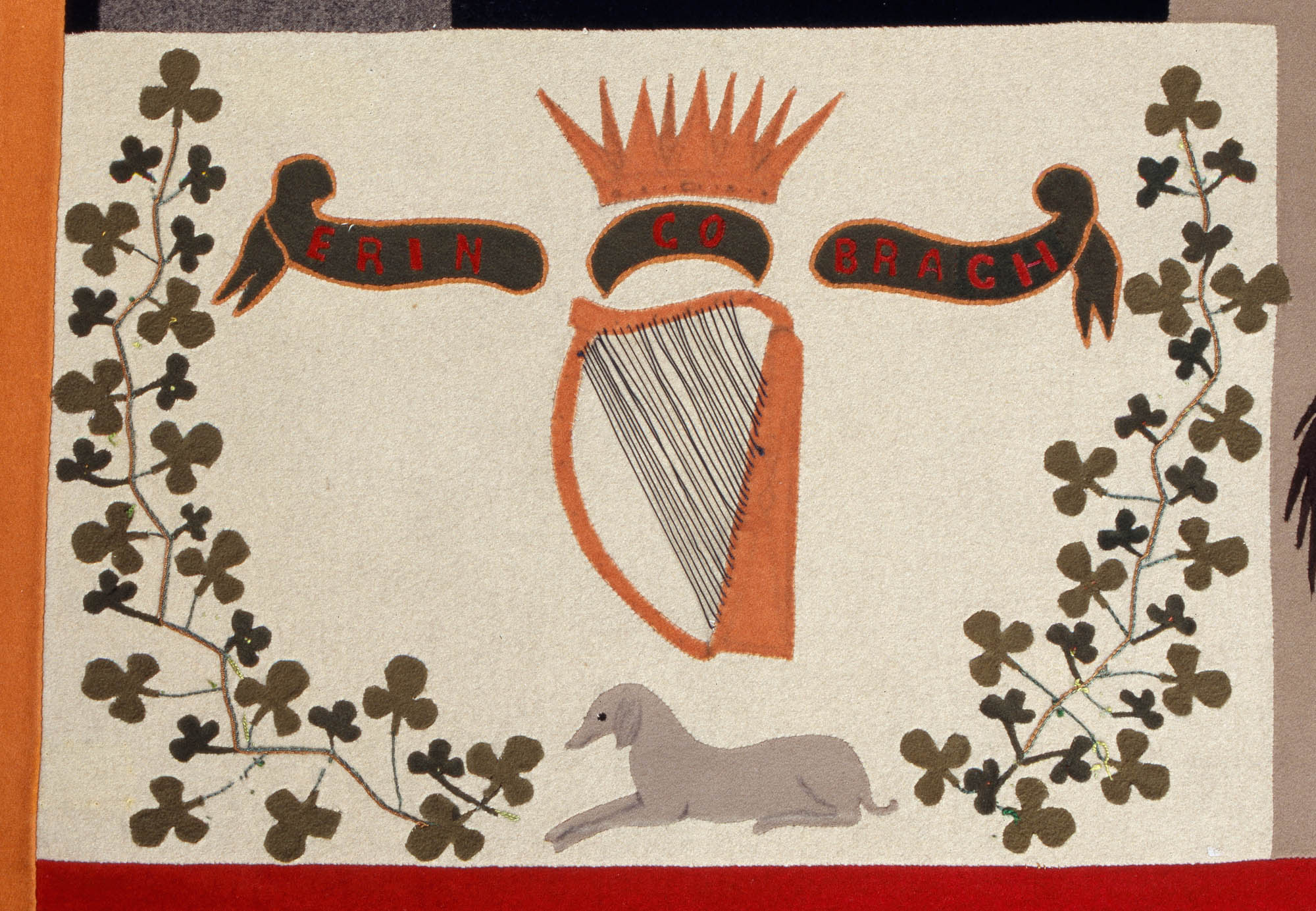 Close-up of a panel on the Stokes Tapestry depicting a harp and crown in the middle with springs of shamrocks on either side. There is a banner that reads "Erin Go Bragh" in the middle and a wolfhound lying down on the bottom.
